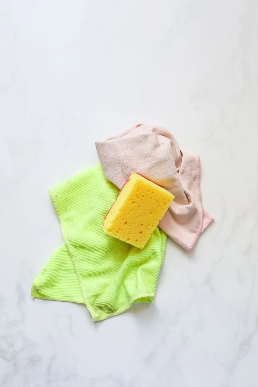 Folded microfibre cloths and a sponge on a white worktop
