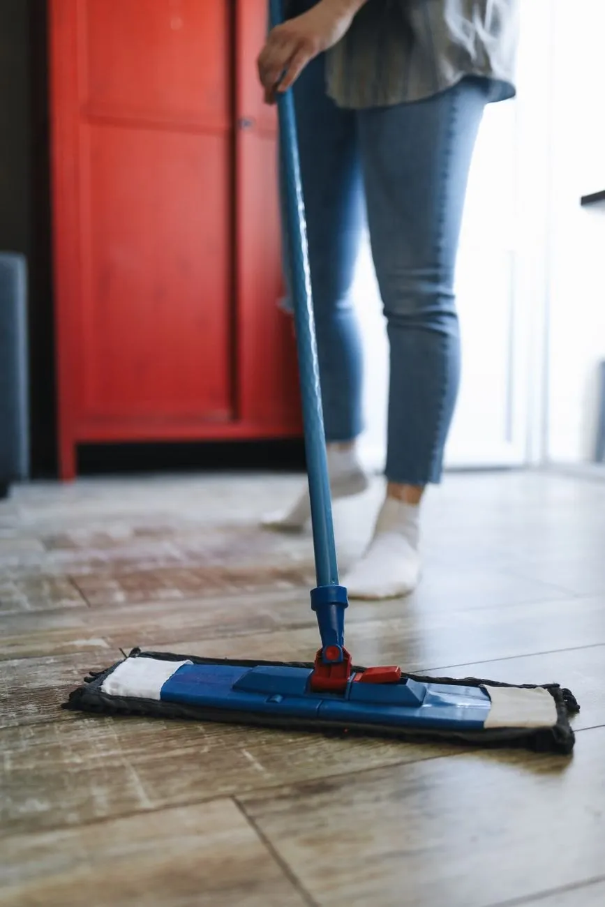 A flat mop being pushed across a wooden floor