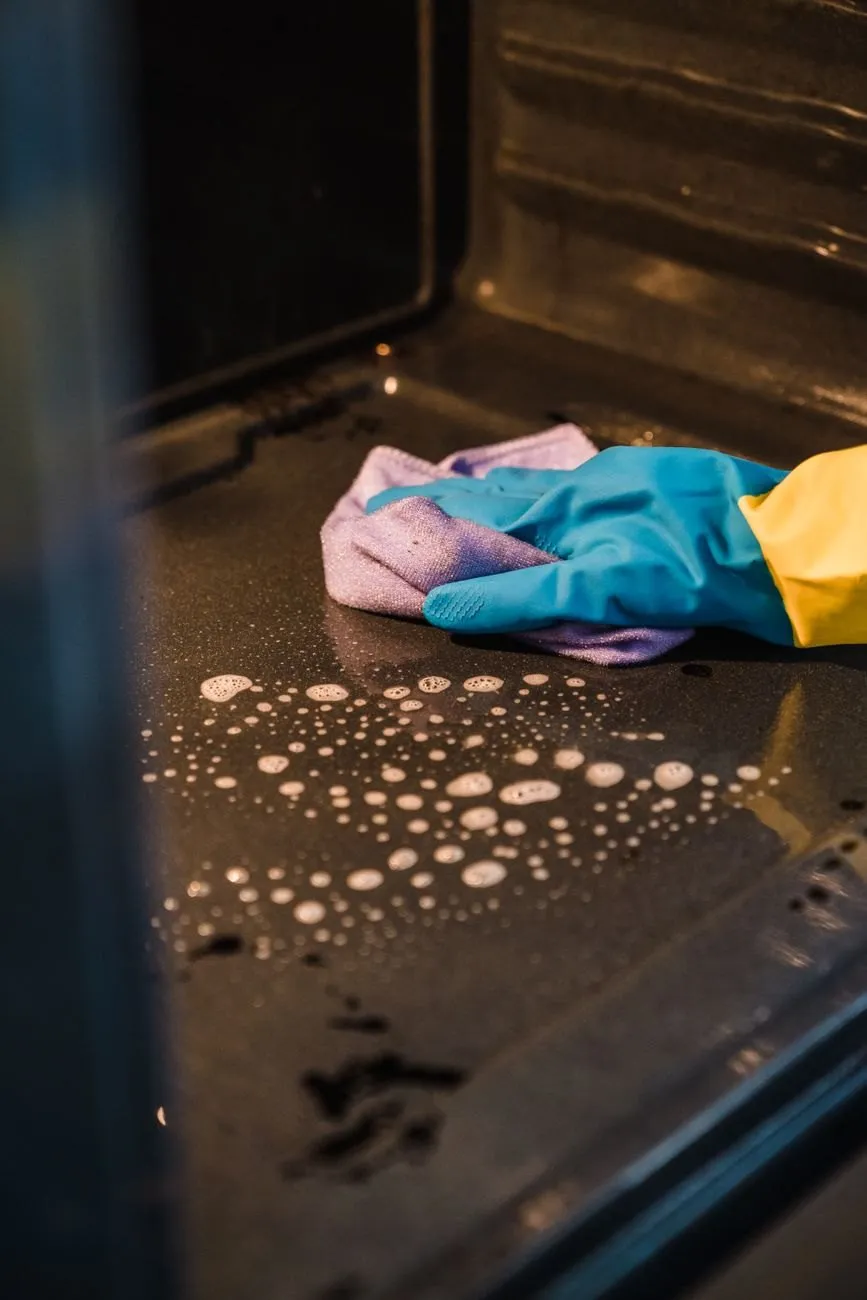 Oven floor covered in grease and cleaning foam before the clean